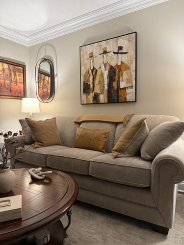 Customer's framed Textured Abstract Figure Art with three figures hanging above a sofa in their living room.