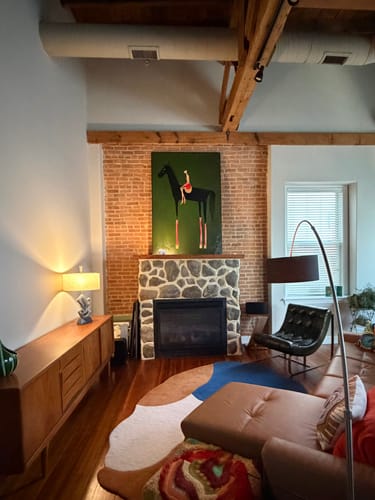 Customer's Textured Equestrian Whimsy painting hanging on a brick wall above a stone fireplace in their living room.